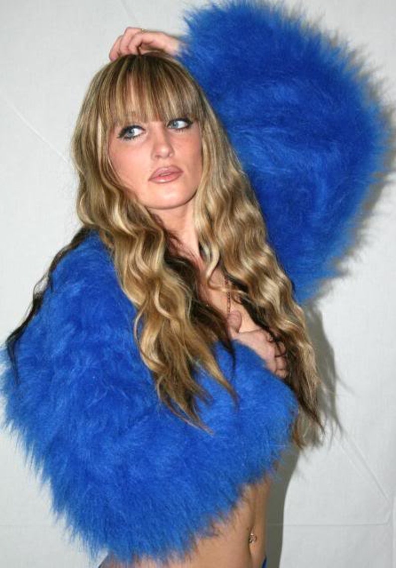Puede incluir: Un su&eacute;ter azul de mohair peludo con mangas largas. El su&eacute;ter es corto y tiene un corte holgado.