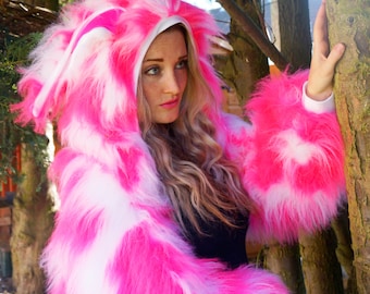 Puede incluir: Una chaqueta con capucha de color rosa y blanco, de pelo sintético, con manga larga. La chaqueta está hecha de piel sintética y tiene un ribete blanco alrededor de la capucha.