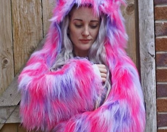 Puede incluir: Una chaqueta con capucha de piel sintética rosa y morada con orejas de gato. La chaqueta está hecha de un material suave y esponjoso y tiene una capucha larga y fluida.