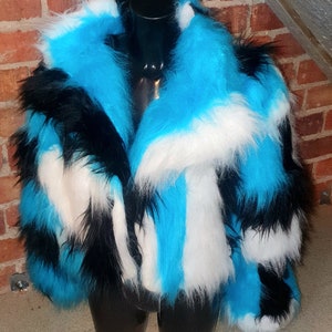 May include: A blue, black and white faux fur jacket with a long, fluffy collar. The jacket is on a black mannequin.
