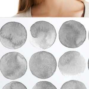 May include: A white canvas print with a pattern of 15 gray watercolor circles. The print is being held by a person's hands. The text "Size 2" is visible in the top left corner of the image.
