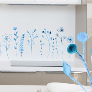 May include: A white kitchen backsplash with a blue watercolour floral design. The design features various blue flowers, leaves, and stems.