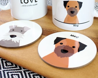 May include: Two white ceramic mugs with dog illustrations and text. One mug says "all you need is LOVE...and a schnauzer". The other mug has a brown and black dog illustration and the name "Meg" below it. Two round coasters with dog illustrations. One coaster has a gray schnauzer illustration and the other has a brown and black dog illustration with the name "Meg" below it.