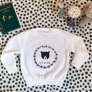 May include: White sweatshirt with a black bear illustration inside a wreath with the text "Ivy Bear".
