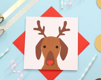 May include: A red card with a white reindeer illustration. The reindeer has brown antlers and a brown face with a red nose.