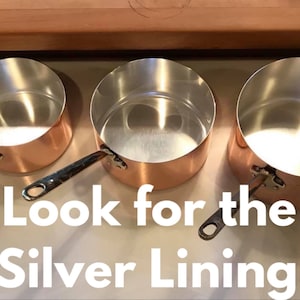 May include: Three copper pots with silver lining interiors. The pots are different sizes and have silver handles. The text "Look for the Silver Lining" is written below the pots.