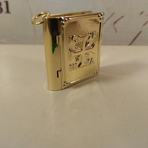 Op de afbeelding: Een gouden metalen boekbedel met een kruisontwerp en de woorden "INRI" aan de voorkant.