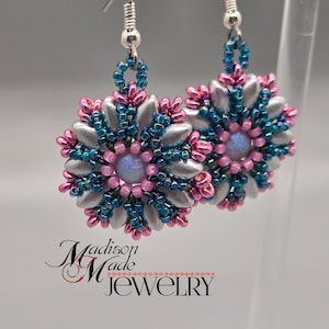 Könnte beinhalten: Ein Paar silberne Ohrringe in Blütenform mit Perlen in den Farben Türkis und Rosa. Die Ohrringe hängen an silbernen Haken.