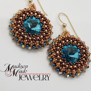 May include: A pair of gold earrings with a teal blue crystal surrounded by brown and gold beads.