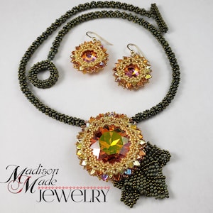 May include: A gold and brown beaded necklace with a large, faceted, orange crystal pendant and matching earrings. The necklace has a tassel-like fringe at the bottom. The text "Madison Made Jewelry" is visible at the bottom of the image.