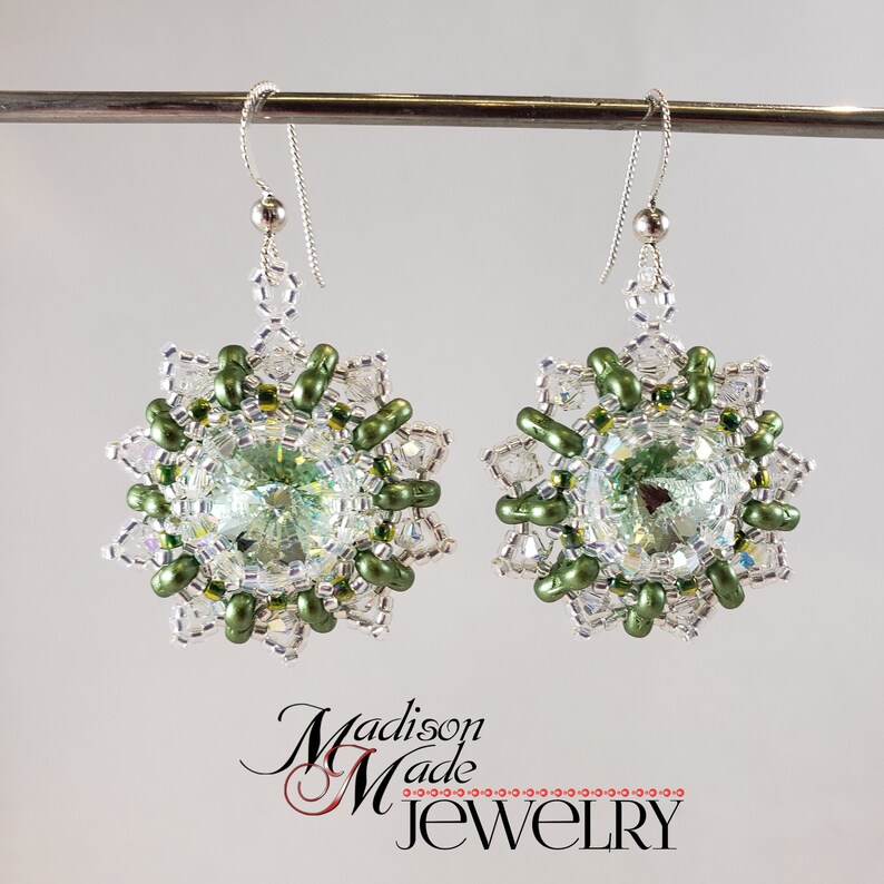 May include: A pair of silver earrings with green and clear crystal beads in a floral design.