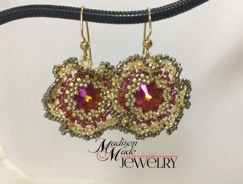 May include: Gold earrings with a pink crystal center and a beaded design. The earrings are in the shape of a flower.