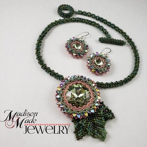 May include: A green beaded necklace with a large green and pink crystal pendant and matching earrings. The pendant has a leaf design. The text "Madison Made Jewelry" is in the lower left corner of the image.
