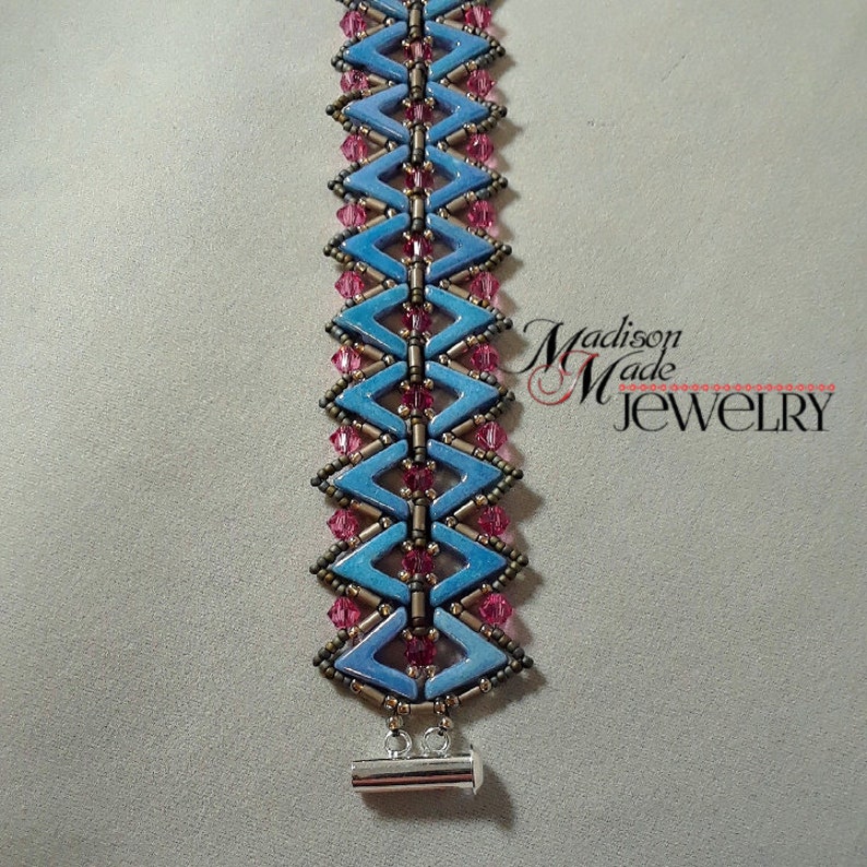 May include: A blue and pink beaded bracelet with a silver toggle clasp. The bracelet is made with small, faceted beads and has a chevron pattern.