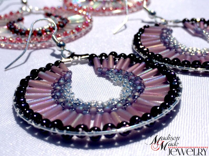 May include: A pair of hoop earrings with a silver wire base and a design of purple and black beads. The beads are arranged in a fan shape, with the purple beads on the outside and the black beads on the inside.