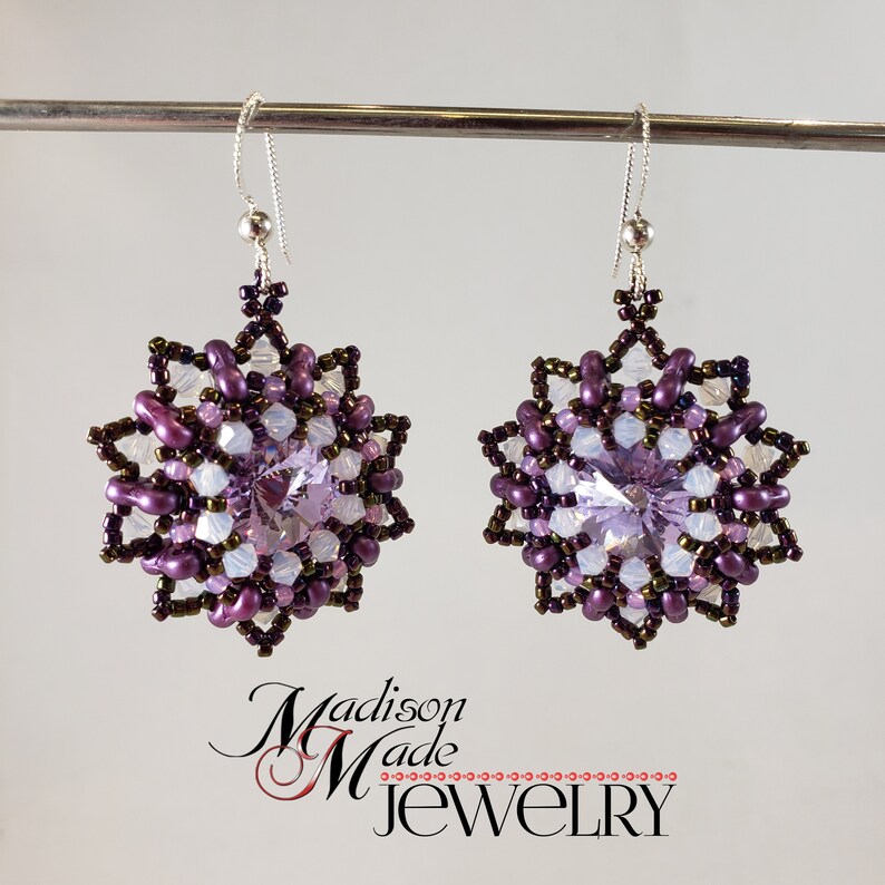 May include: Purple and white beaded earrings with a clear crystal centre. The earrings are in the shape of a starburst.