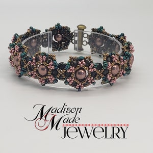 May include: A beaded bracelet with a geometric design featuring black, gold, green, and pink beads. The bracelet has a clasp closure.