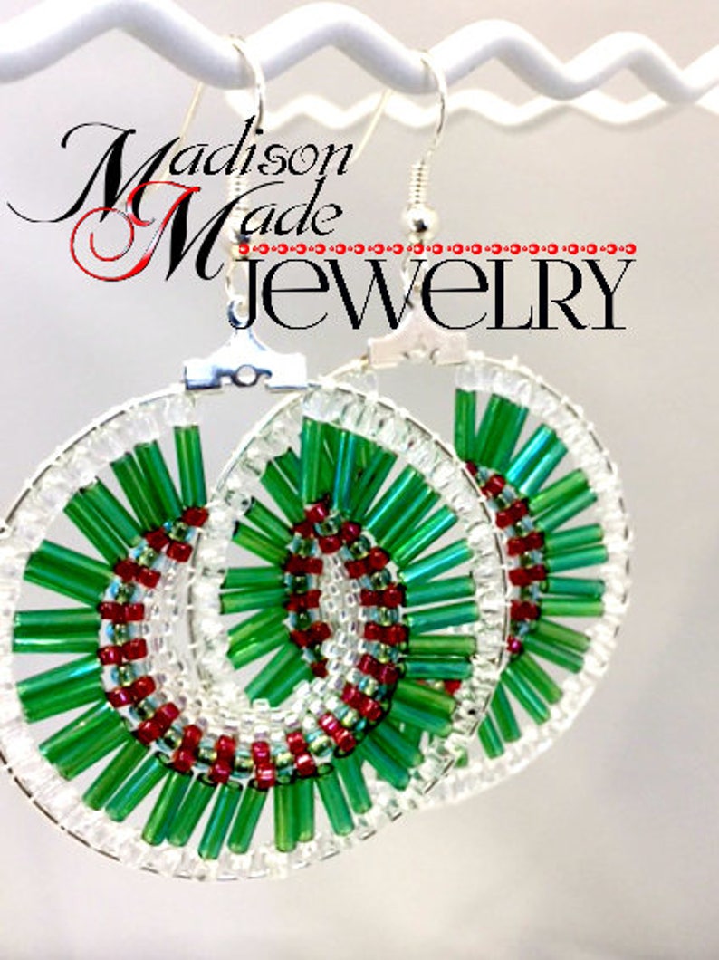 May include: A pair of green and red beaded earrings with a spiral design. The earrings are made with small, round beads and are attached to silver hooks.