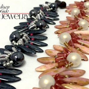 May include: Two strands of beaded jewelry, one in black and silver with red accents, and the other in pink, gold, and white. The jewelry is made with small, teardrop-shaped beads.