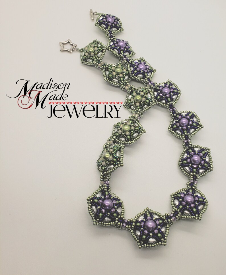 May include: A delicate necklace with a geometric design featuring alternating green and purple star-shaped beads. The necklace is made with small seed beads and larger pearl-like beads.