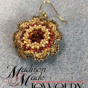 May include: A gold beaded earring with a red and gold center and a brown beaded border. The earring is hanging from a gold wire.