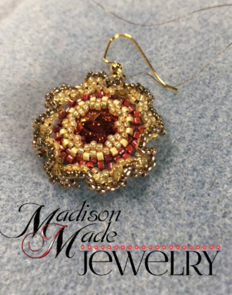 May include: A gold beaded earring with a red and gold center and a brown beaded border. The earring is hanging from a gold wire.