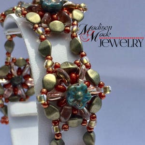 May include: A beaded bracelet with a multi-colored design featuring brown, gold, red, and blue beads. The bracelet is made with a variety of different sized beads and has a unique, intricate design. The bracelet is on a white display stand.  Madison Made Jewelry.