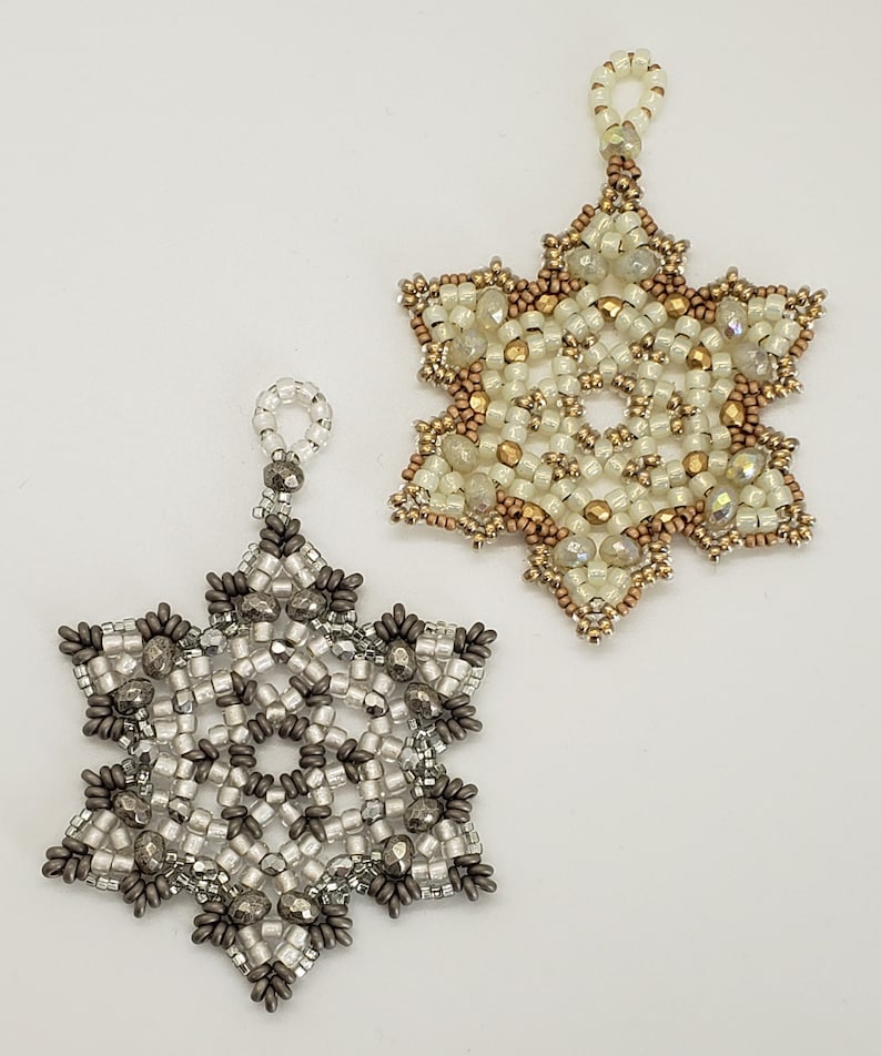 May include: Two beaded snowflake ornaments, one with silver and white beads and the other with gold and white beads.