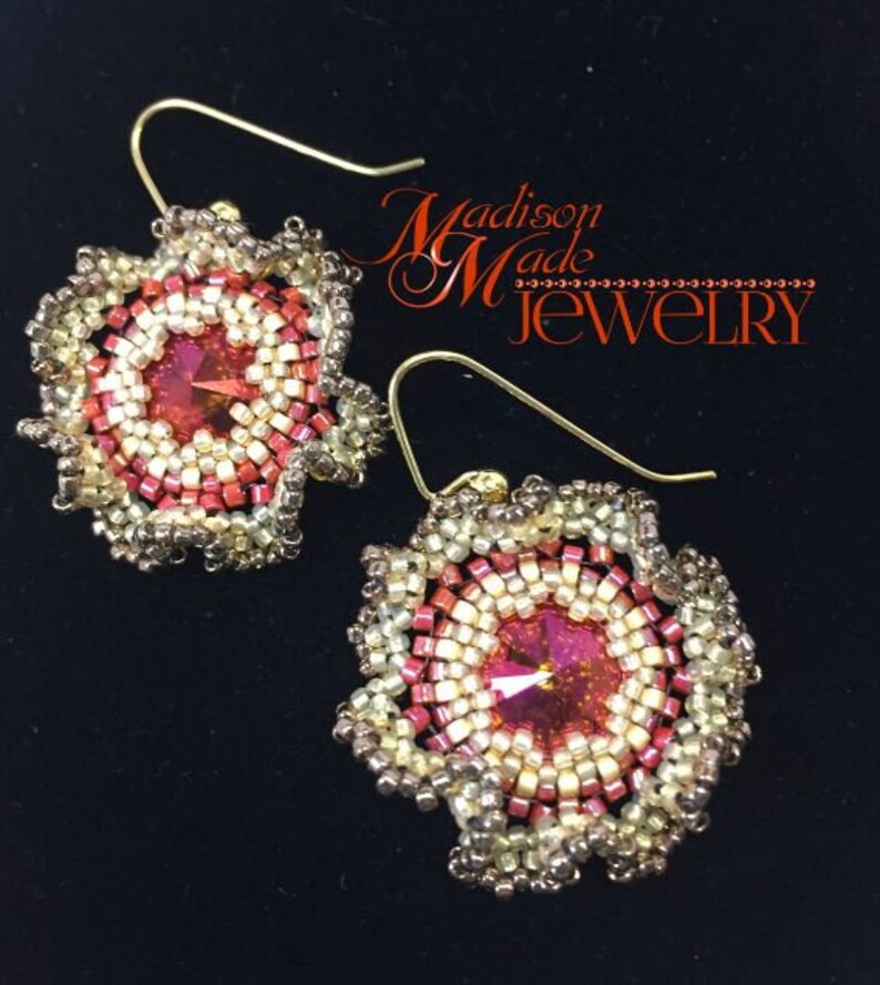 May include: A pair of gold earrings with a red and white beaded flower design. The center of each flower has a red crystal. The earrings are labeled "Madison Made Jewelry".