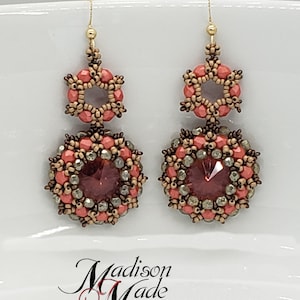 May include: A pair of dangle earrings with a peach and brown color scheme. The earrings feature a round bead with a crystal center and a smaller hexagonal bead above it.