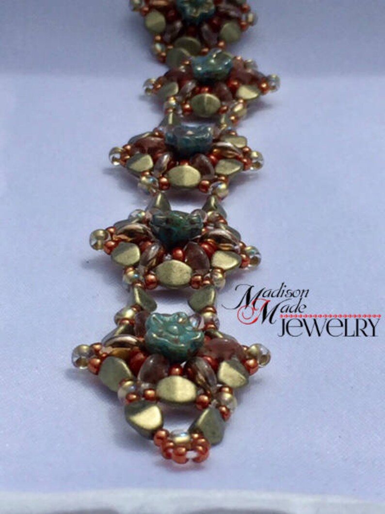 May include: A gold, brown, and green beaded bracelet with a flower design. The bracelet is made with small, round beads and has a delicate, intricate design. The bracelet is accented with a small, turquoise-colored bead in the center of each flower.
