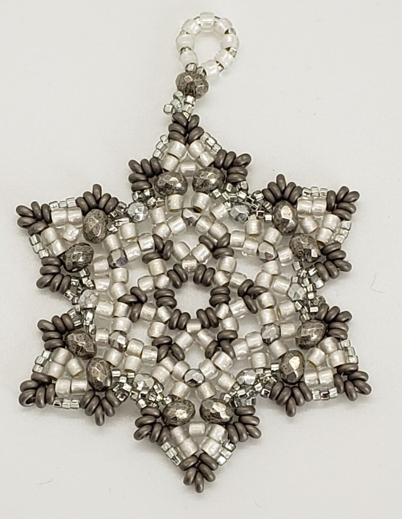 May include: A silver and gray beaded snowflake ornament with a loop for hanging.