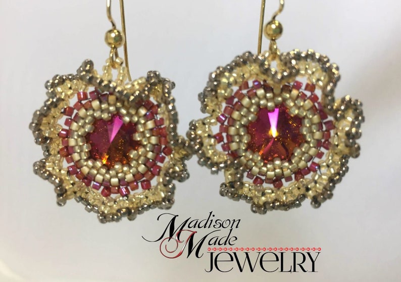 May include: A pair of gold earrings with a pink and gold beaded design. The earrings feature a round, iridescent pink crystal in the center of each earring.