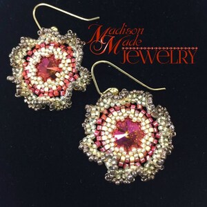 May include: A pair of gold earrings with a red, white, and gold beaded flower design. The earrings feature a red crystal in the center of each flower.