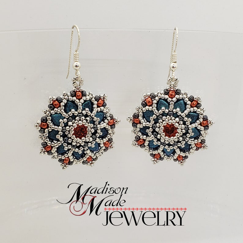 May include: A pair of handmade beaded earrings. Each earring features a floral design with teal, red, and silver beads. The earrings are suspended from silver-colored ear wires. The text "Madison Made Jewelry" is visible.