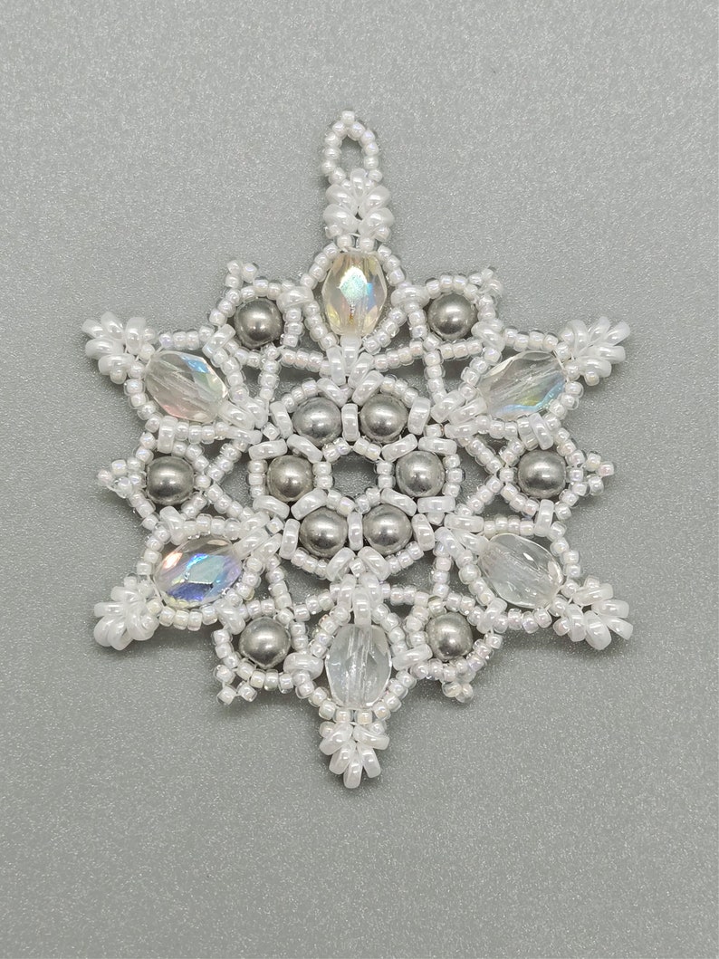 May include: A white and silver beaded snowflake ornament with a loop for hanging.