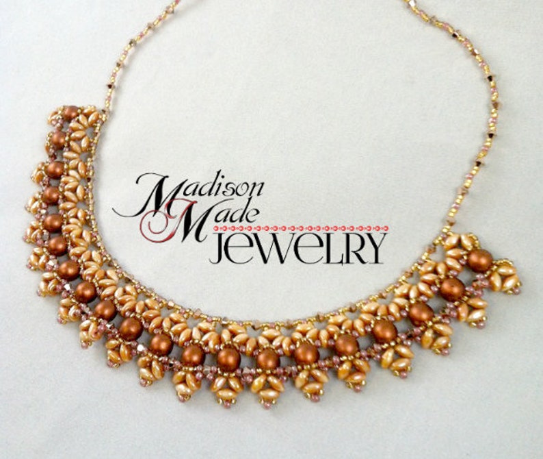May include: A delicate gold and brown beaded necklace with a layered design. The necklace features small, round beads and larger, oval beads. The necklace is made by Madison Made Jewelry.