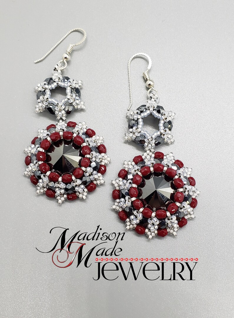 May include: A pair of silver dangle earrings with a red and silver beaded design. The earrings feature a large, faceted black crystal in the center of each earring.