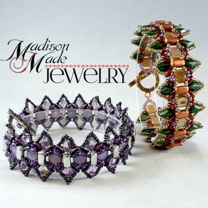 May include: Two beaded bracelets. One is purple, silver, and clear, with a silver clasp. The other is green, copper, and gold, with a gold clasp. The bracelets are displayed on a clear stand. The text "Madison Made Jewelry" is in the upper left.
