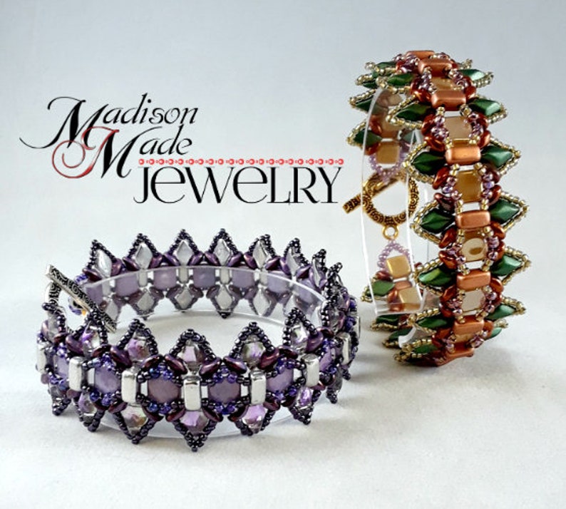 May include: Two beaded bracelets. One is purple, silver, and clear, with a silver clasp. The other is green, copper, and gold, with a gold clasp. The bracelets are displayed on a clear stand. The text "Madison Made Jewelry" is in the upper left.