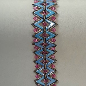 May include: A blue and pink beaded bracelet with a silver clasp. The bracelet is made with small, faceted beads in a geometric pattern.