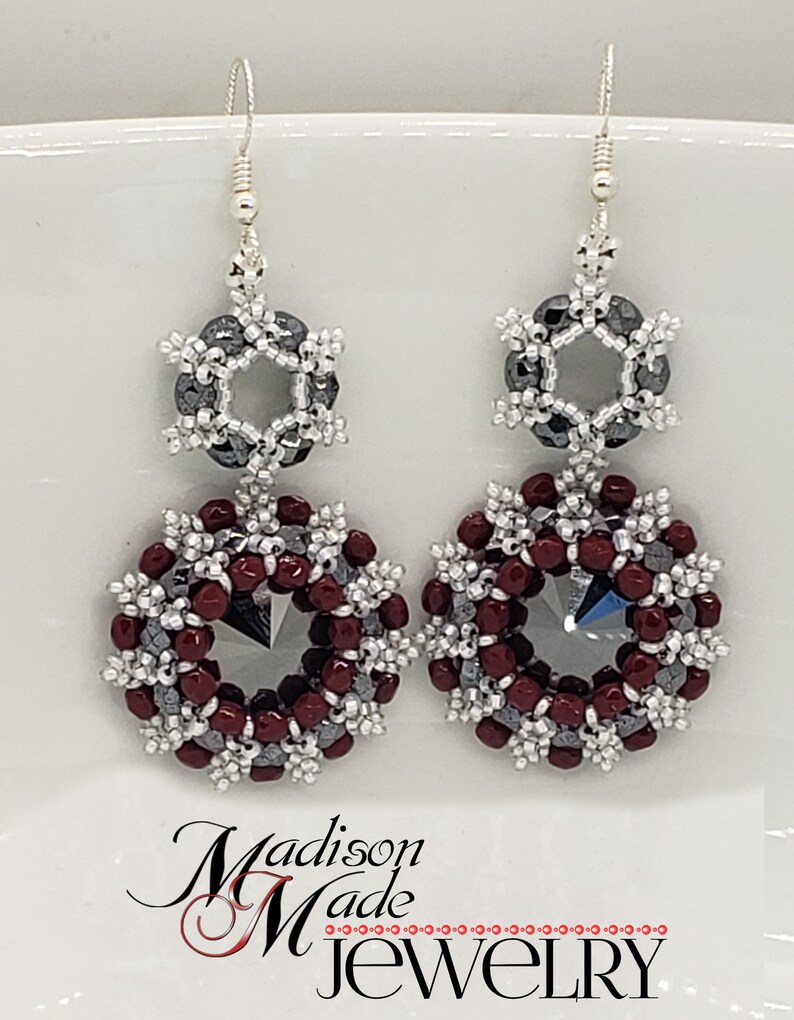 May include: A pair of silver earrings with a burgundy and silver bead design. The earrings feature a hexagonal bead surrounded by smaller beads in a snowflake pattern.
