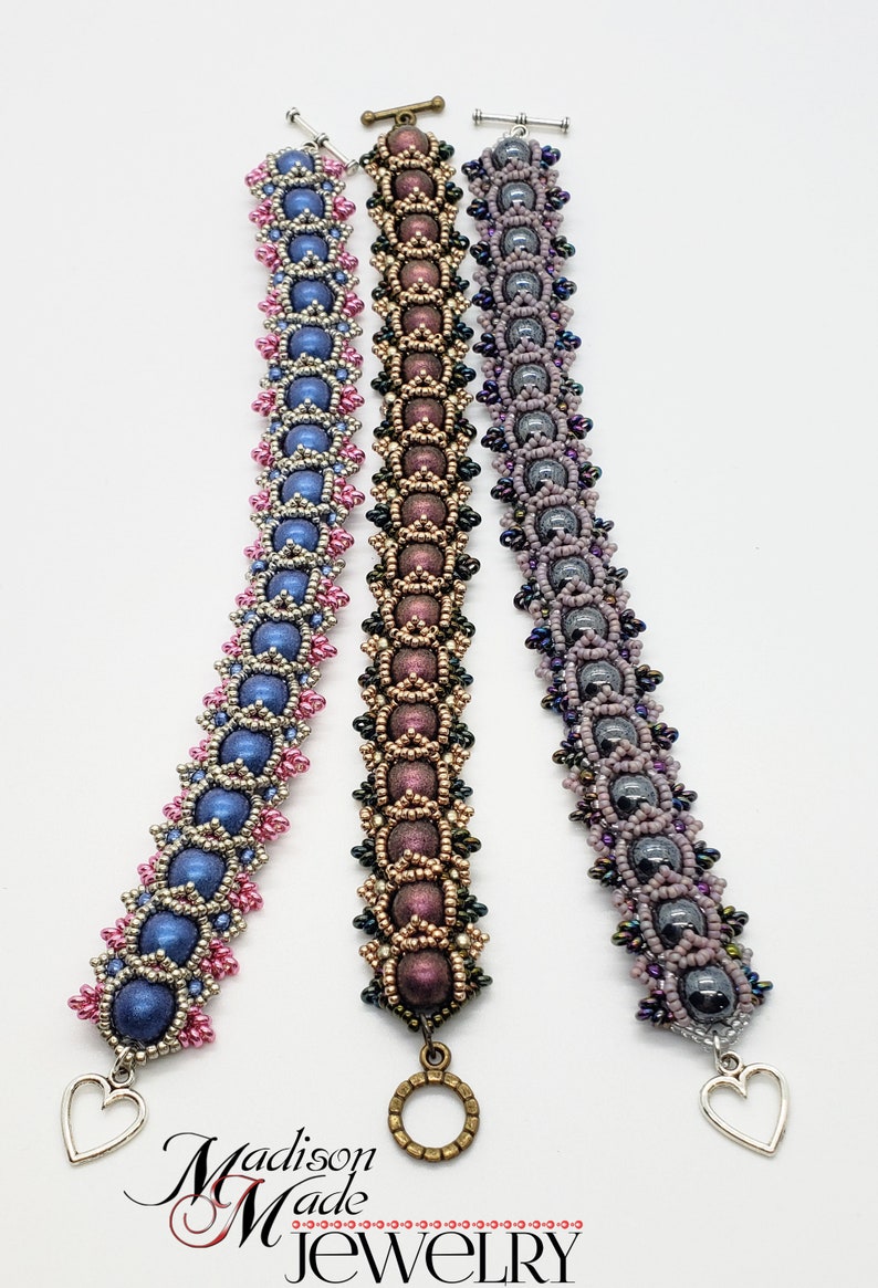 May include: Three beaded bracelets with different colored beads and clasps. The bracelets are made with small, round beads in shades of blue, pink, and purple. The clasps are silver, gold, and heart-shaped.