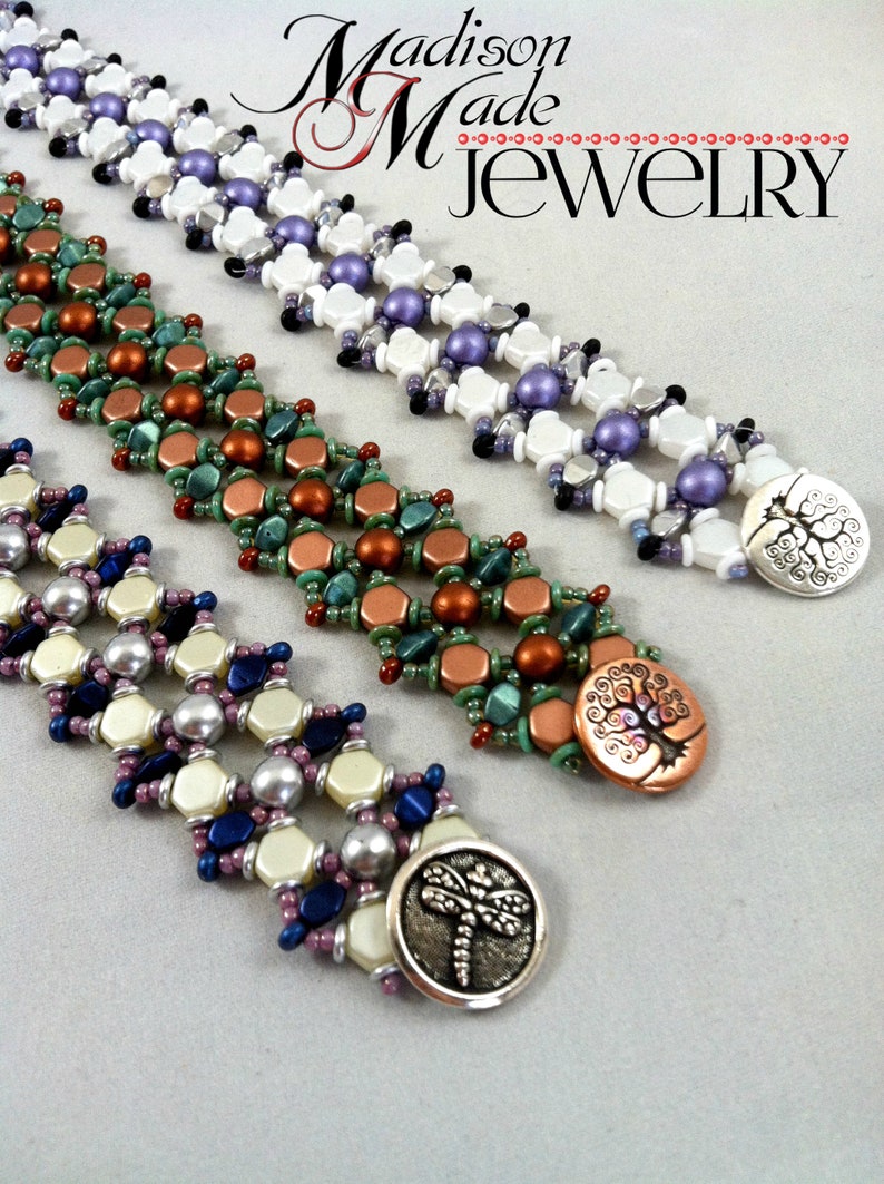 Op de afbeelding: Drie kralenarmbanden met kralen in verschillende kleuren en decoratieve metalen sluitingen. De sluitingen tonen een boom, een libel en een boom met spiralen. De armbanden zijn gelabeld met "Madison Made Jewelry".