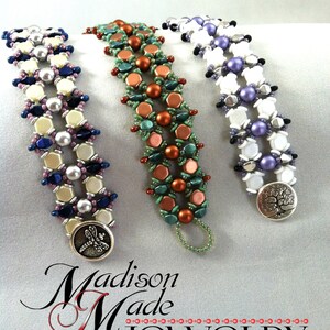 Op de afbeelding: Drie kralenarmbanden met verschillende kleurcombinaties. De armbanden zijn gemaakt van witte, paarse, groene, koperen en bruine kralen. De armbanden hebben zilveren sluitingen met een libellen- en een boomontwerp.