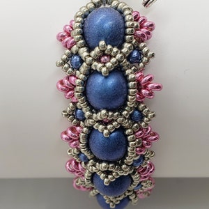 May include: A blue beaded bracelet with silver and pink beads. The bracelet has a toggle clasp. The bracelet is made by Madison Made Jewelry.