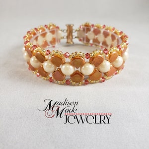 Op de afbeelding: Een kralenarmband met een gouden sluiting, bestaande uit een dubbele rij cr&egrave;mekleurige kralen en een rij gouden en roze kralen.