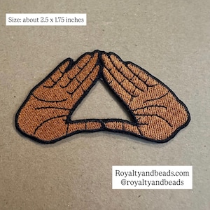 May include: Embroidered patch featuring two hands forming a triangle, with a brown and black color scheme. The patch measures approximately 2.5 x 1.75 inches. The text "Royaltyandbeads.com @royaltyandbeads" is printed at the bottom.