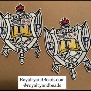 May include: Two white embroidered patches with a crest featuring a book, a skull, and the letters "ΣΓΡ" and "FOUNDED 1922".