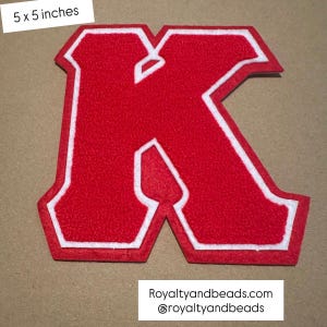 May include: A red felt letter "K" patch with a white border, measuring 5 x 5 inches. The patch has a textured surface and is displayed on a neutral background. The text "Royaltyandbeads.com @royaltyandbeads" is at the bottom.